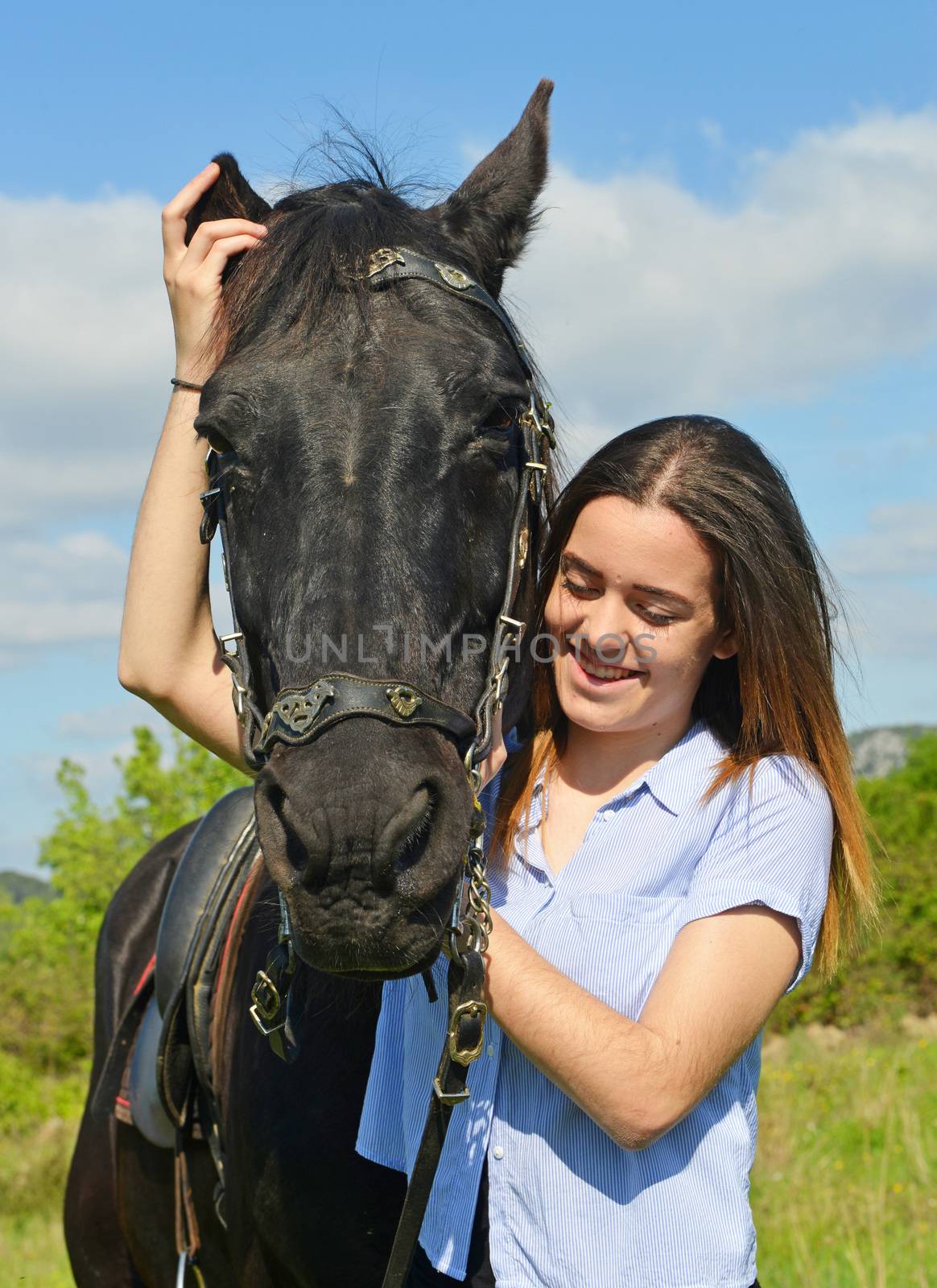 young riding girl and her black stallion in nature