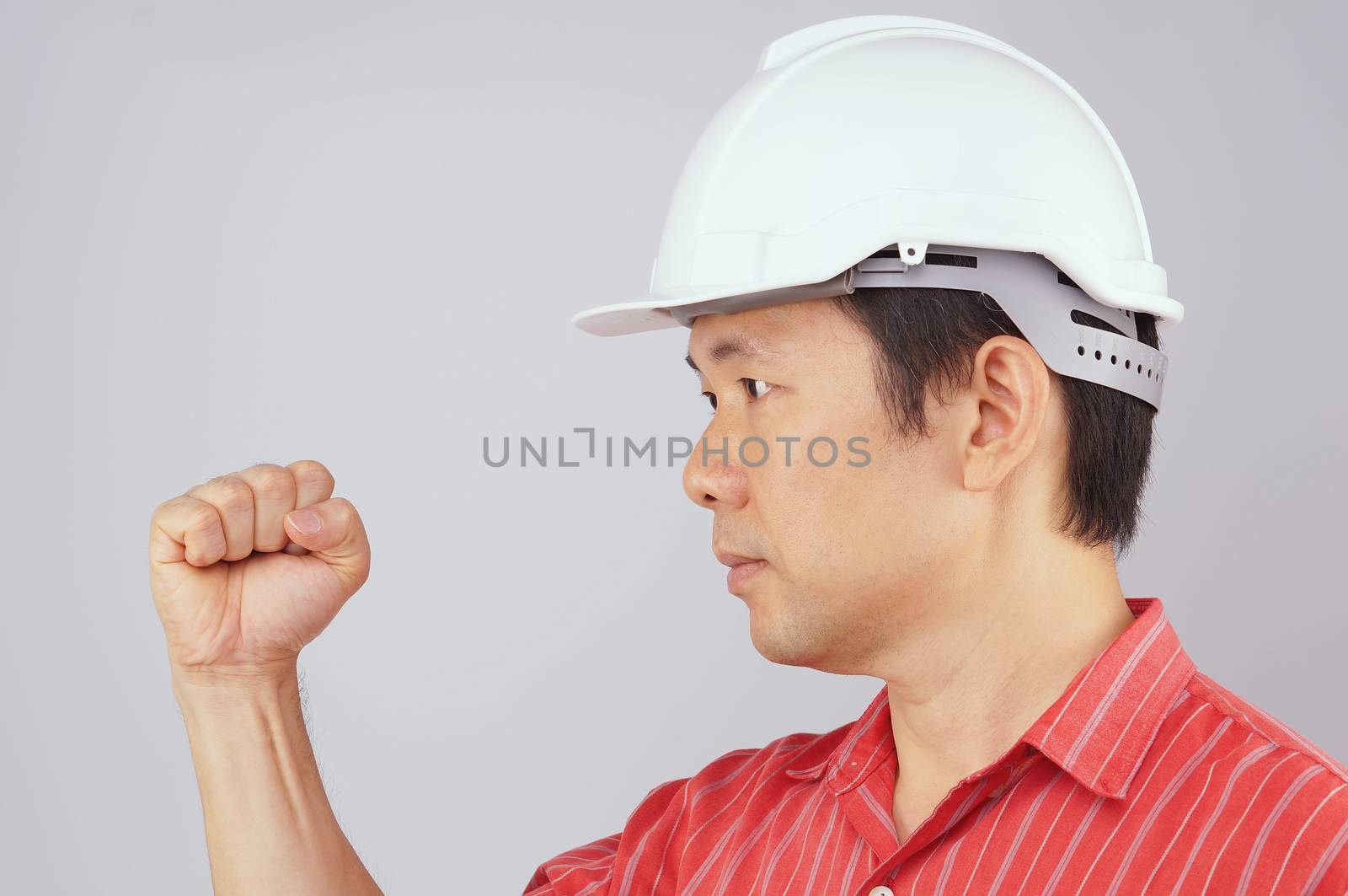 Engineer wear red shirt and white engineer hat make signal by fist on white background.