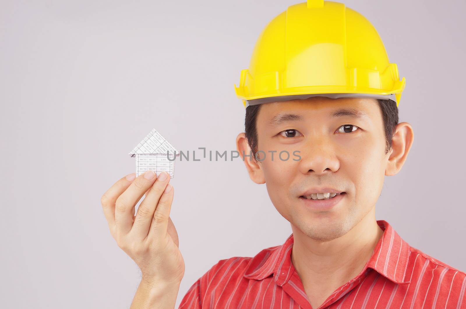 Engineer wear red shirt and yellow engineer hat holding house on white background.