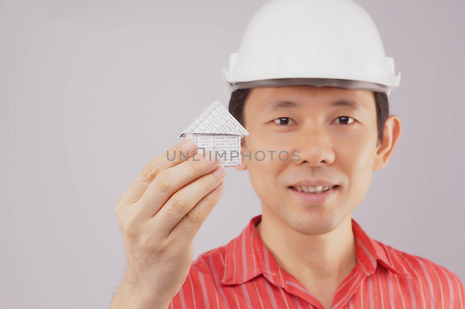 Hand of man holding house have blur engineer wear red shirt and white engineer hat on white background.