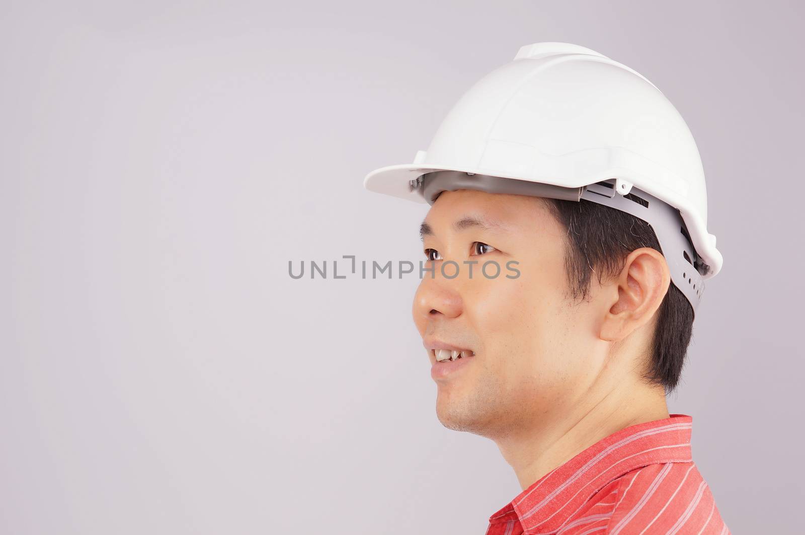 Happy engineer wear red shirt and white engineer hat look to the side on white background.