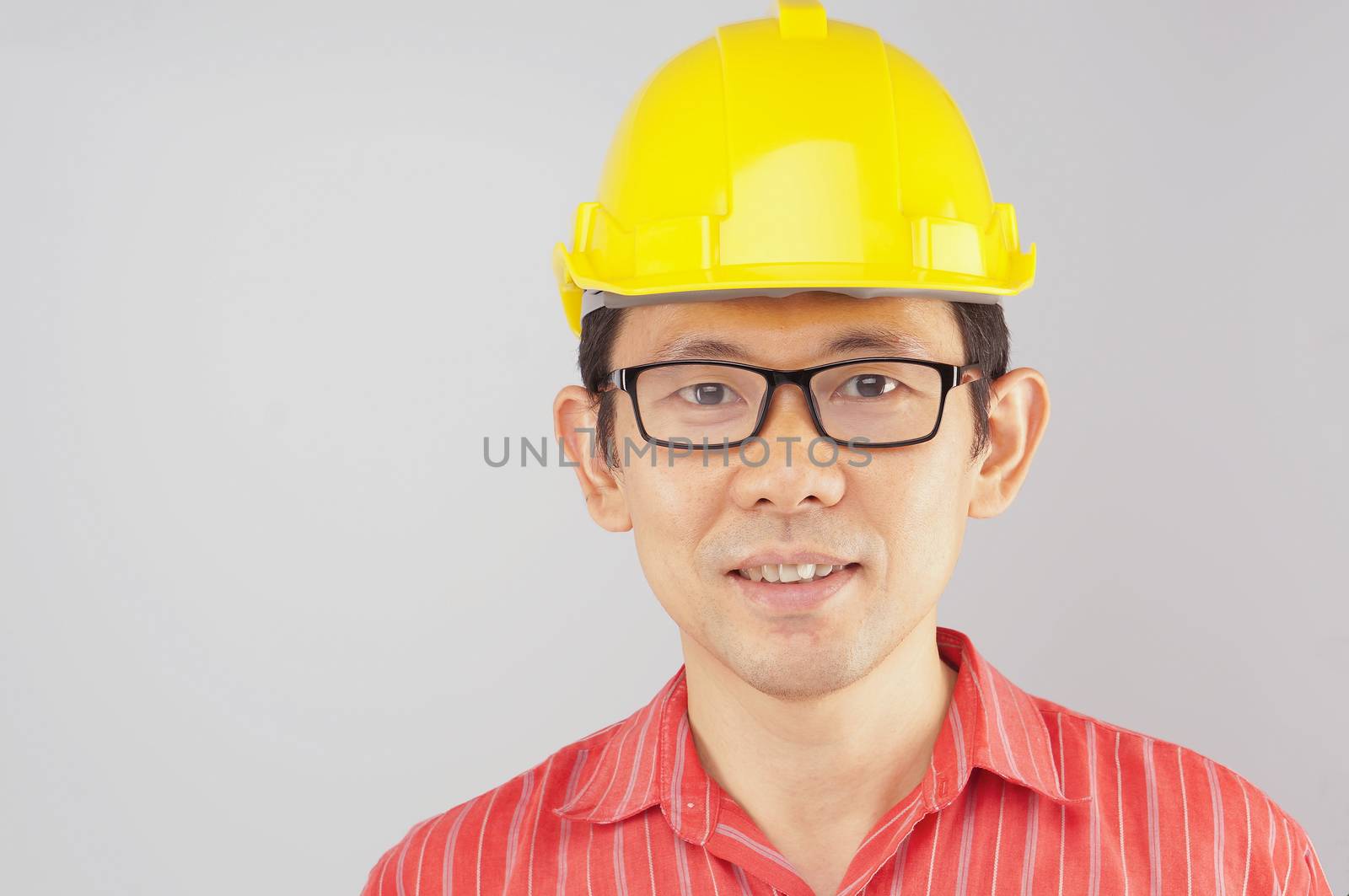 Happy engineer wear red shirt and yellow engineer hat with black spectacles look to the front on white background.