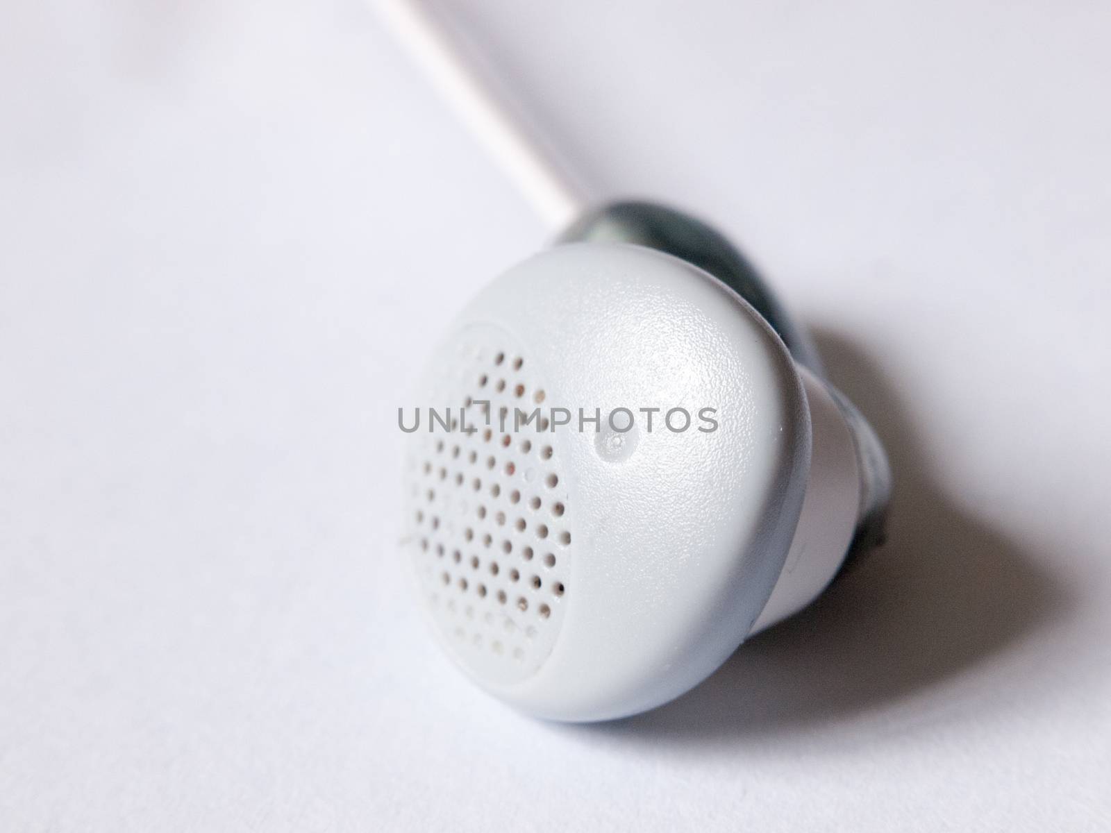 close up of a single ear bud headphone white by callumrc