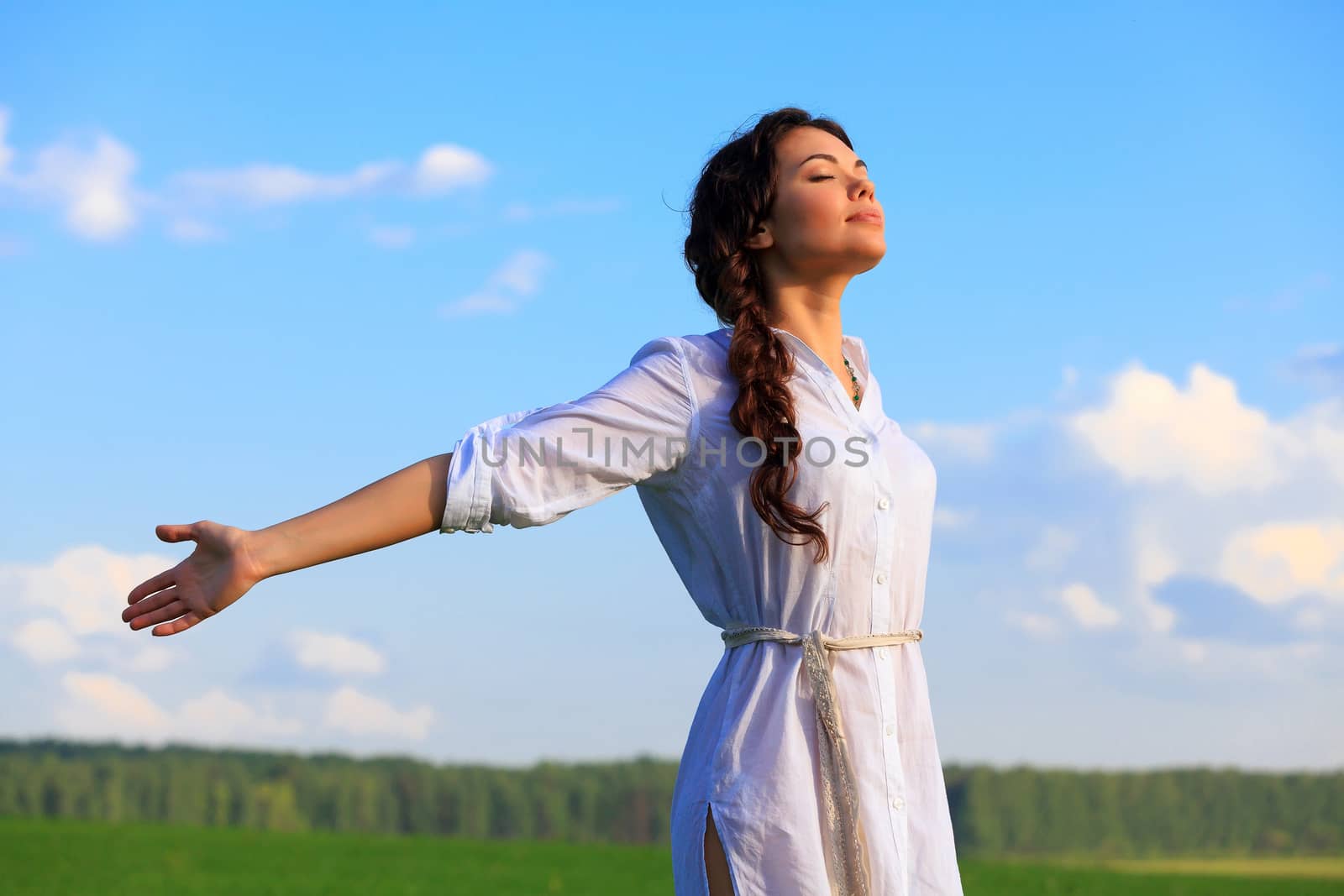 Young happy woman in green field. Green grass and blue sky behind.