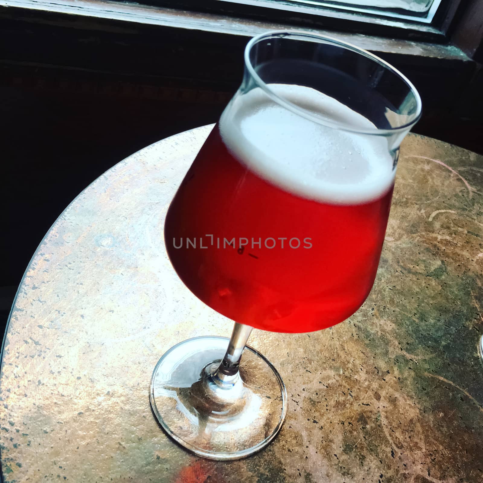 Glass of seasonal cherry beer on a bar table. Delicious.