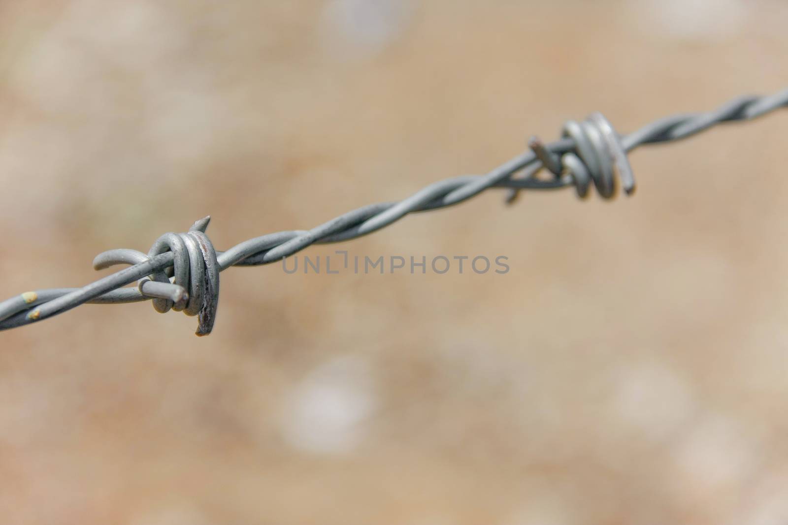 closeup barbed fence with ground on background