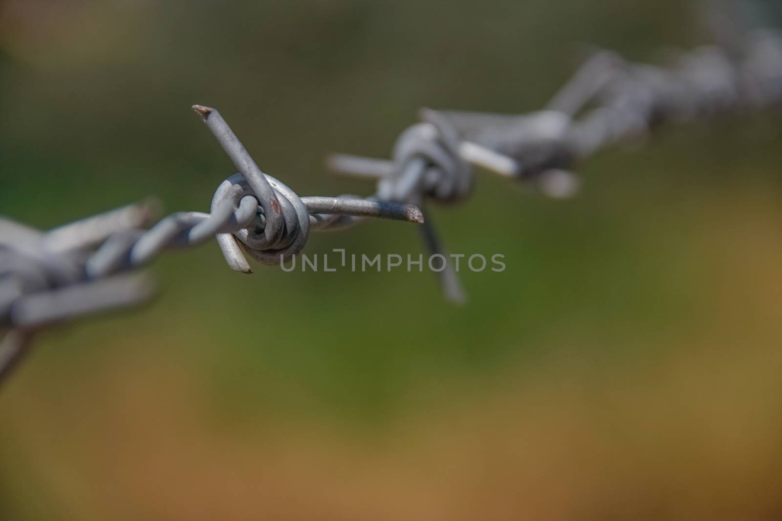 closeup barbed fence with ground on background