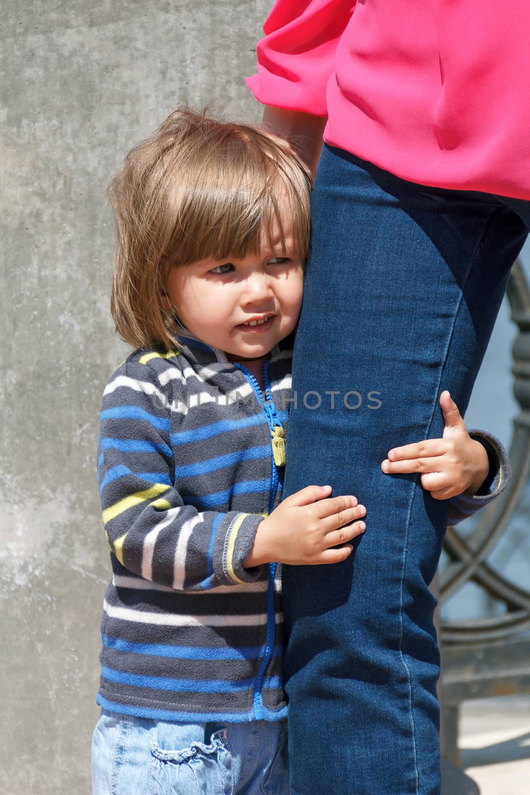 Cute Caucasian girl embrace mother leg in summer