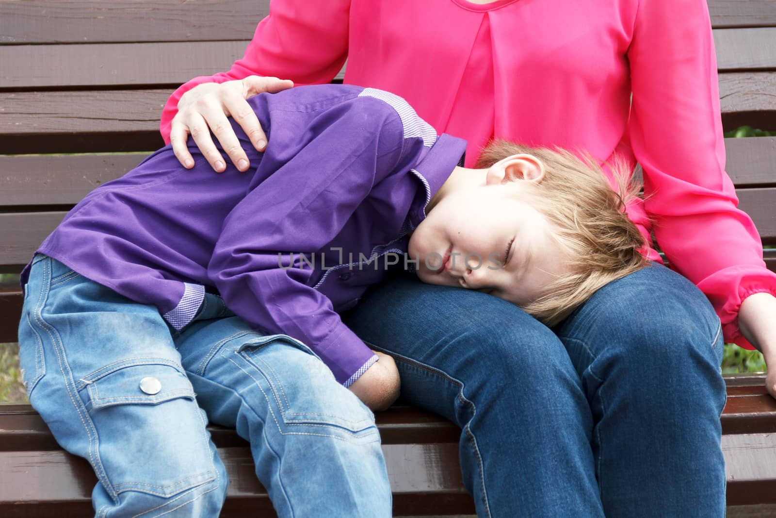 Mother with sleeping son has a rest on bench