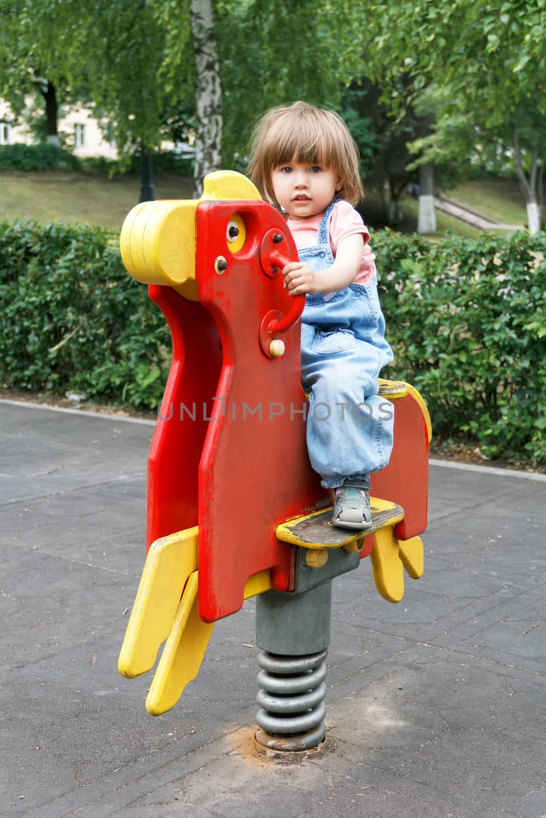 Baby riding on hutches at the playground with disheveled hair