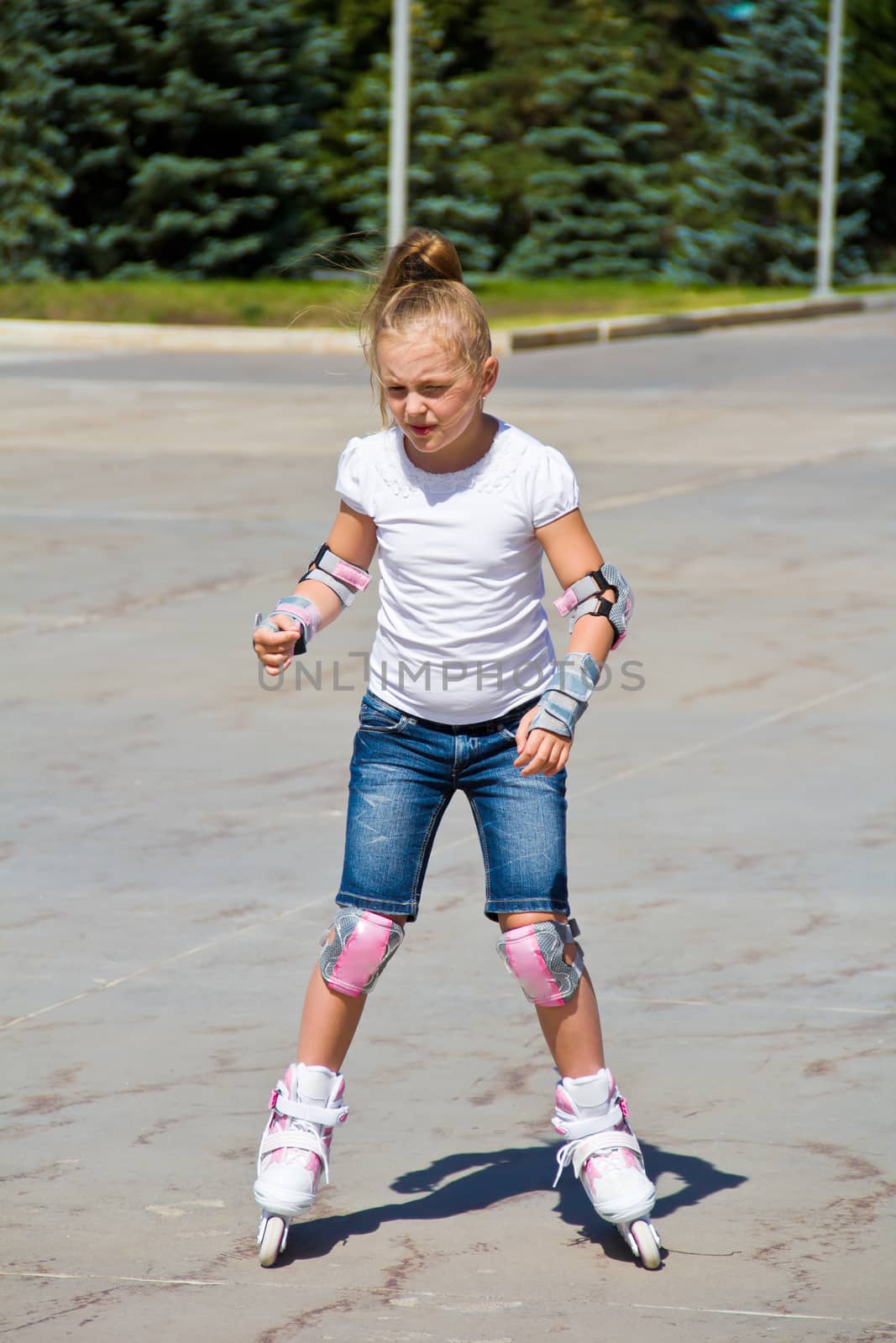 Learning girl on roller skates in summer