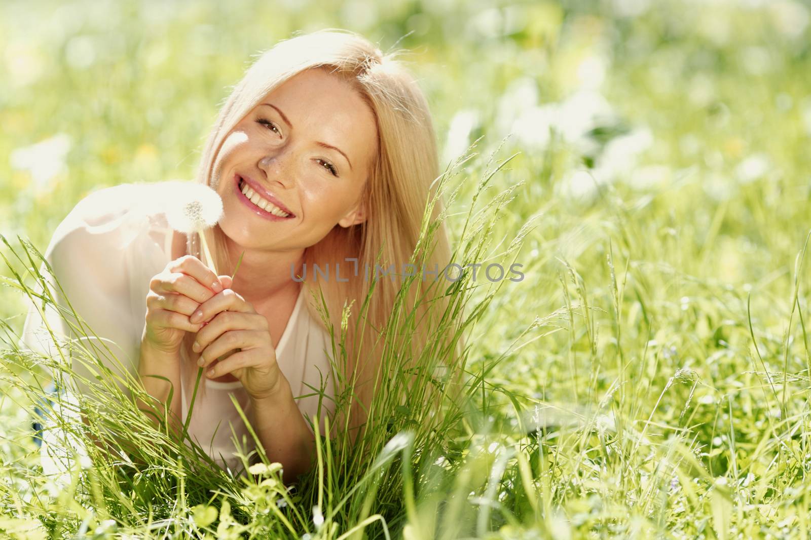 girl with a dandelion in his hand lying on the grass