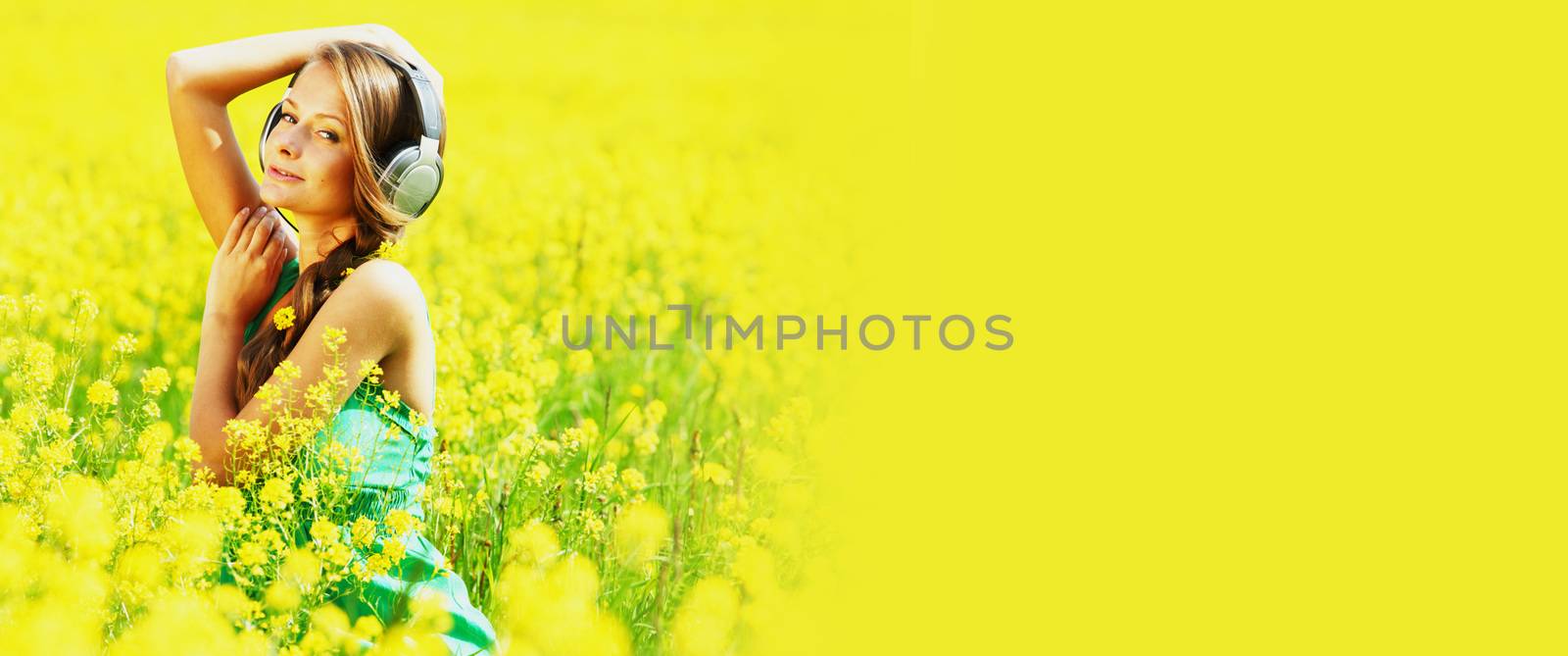 woman listening to music on oilseed field