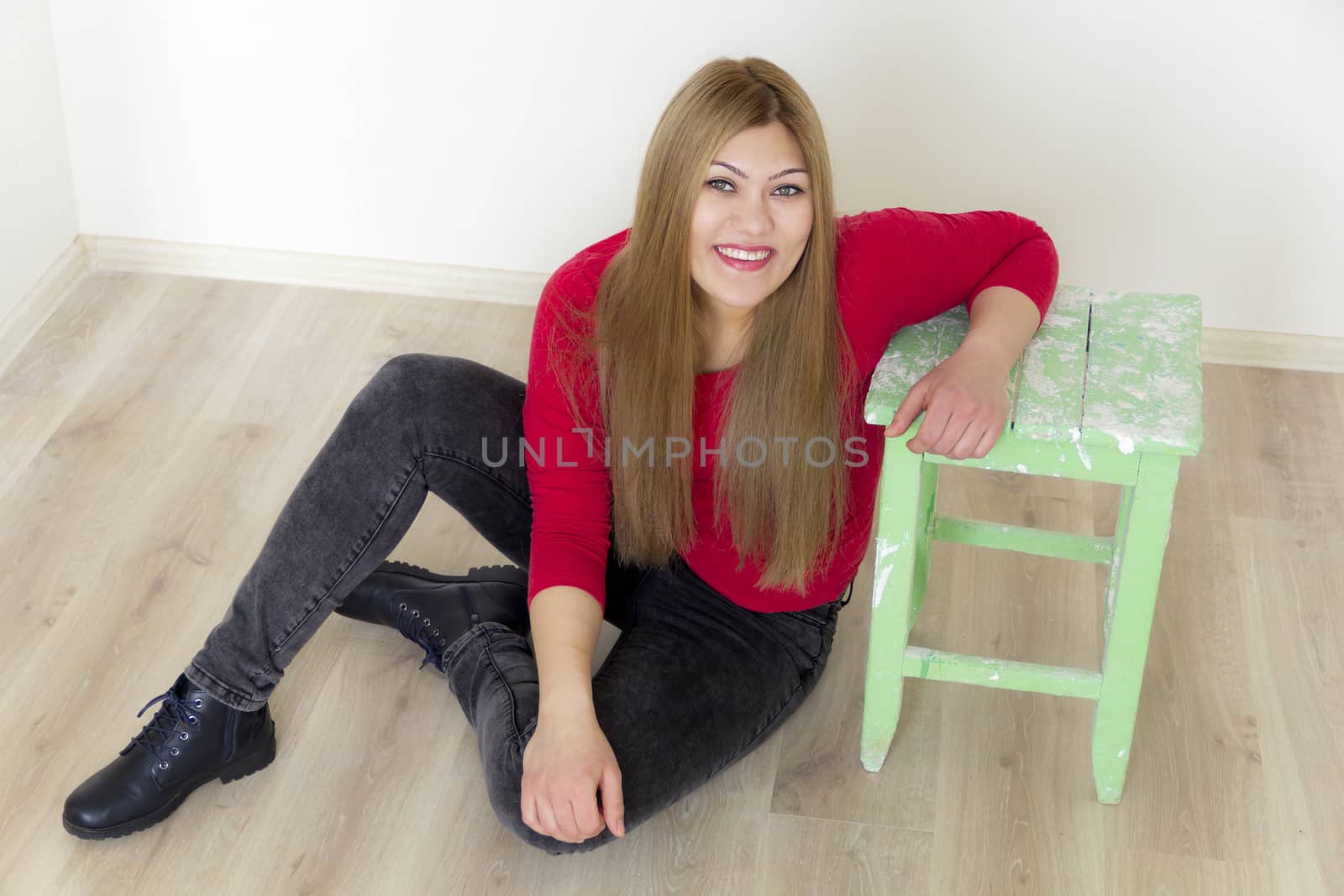Girl with long brown healthy hair sitting on floor in red