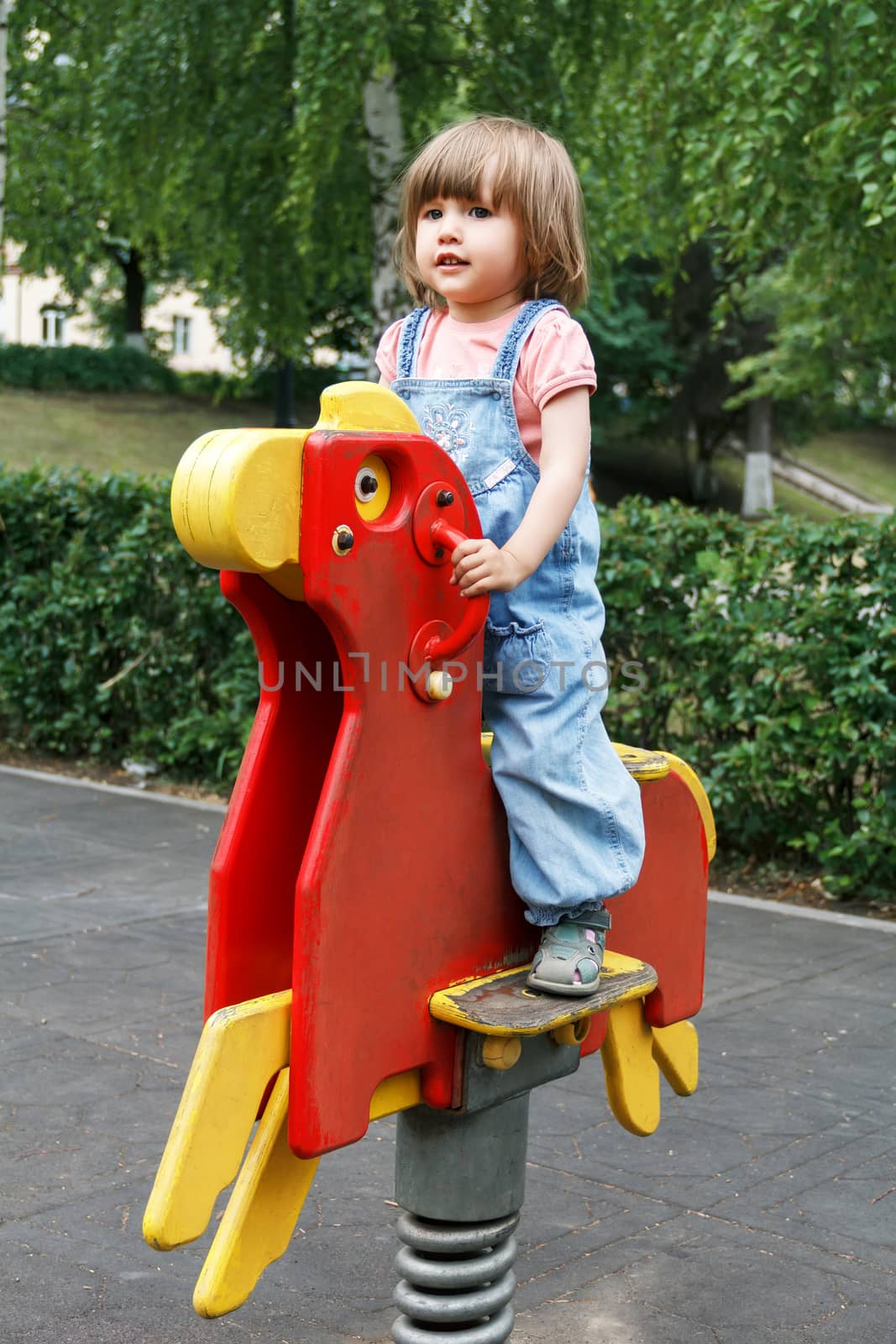 Baby riding on hutches at the playground with disheveled hair
