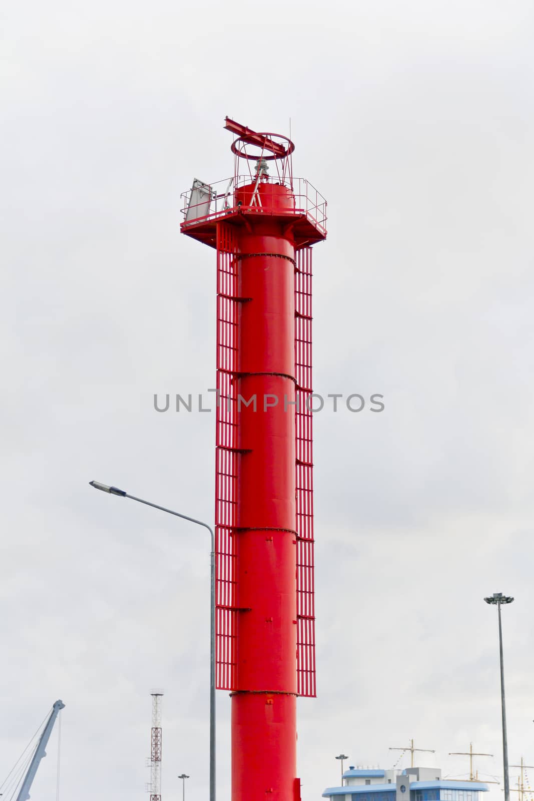 Vertical photo of the high red lighthouse in sea port