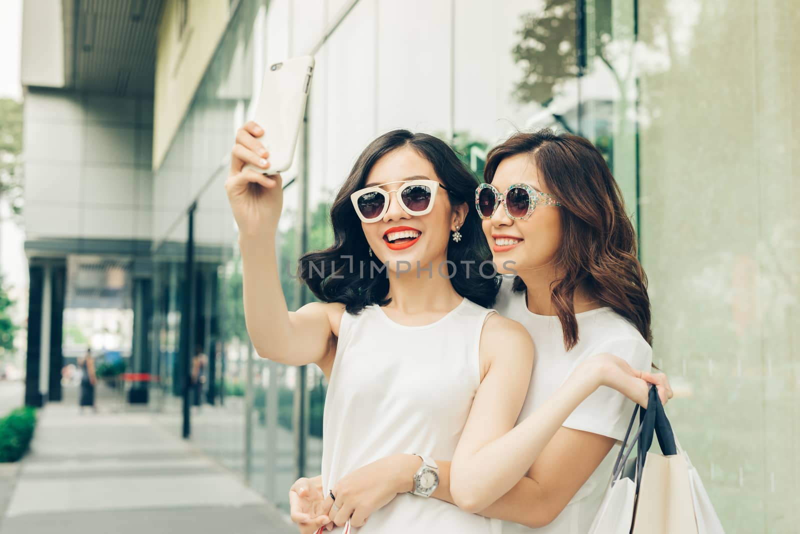 Beautiful asian girls with shopping bags taking selfie photo at the mall