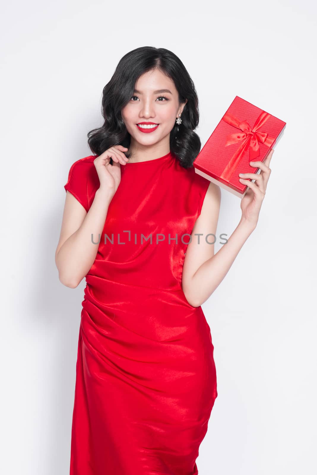Pretty young asian woman dressed in red dress with a present