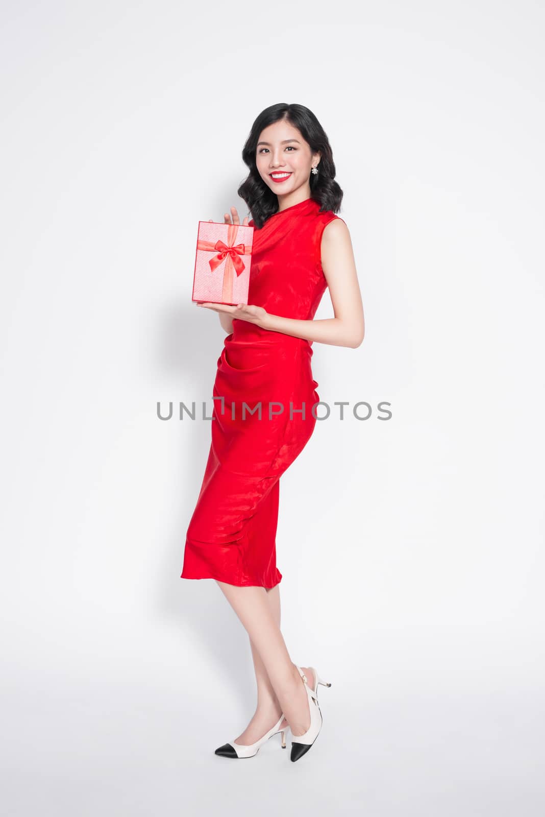 Pretty young asian woman dressed in red dress with a present