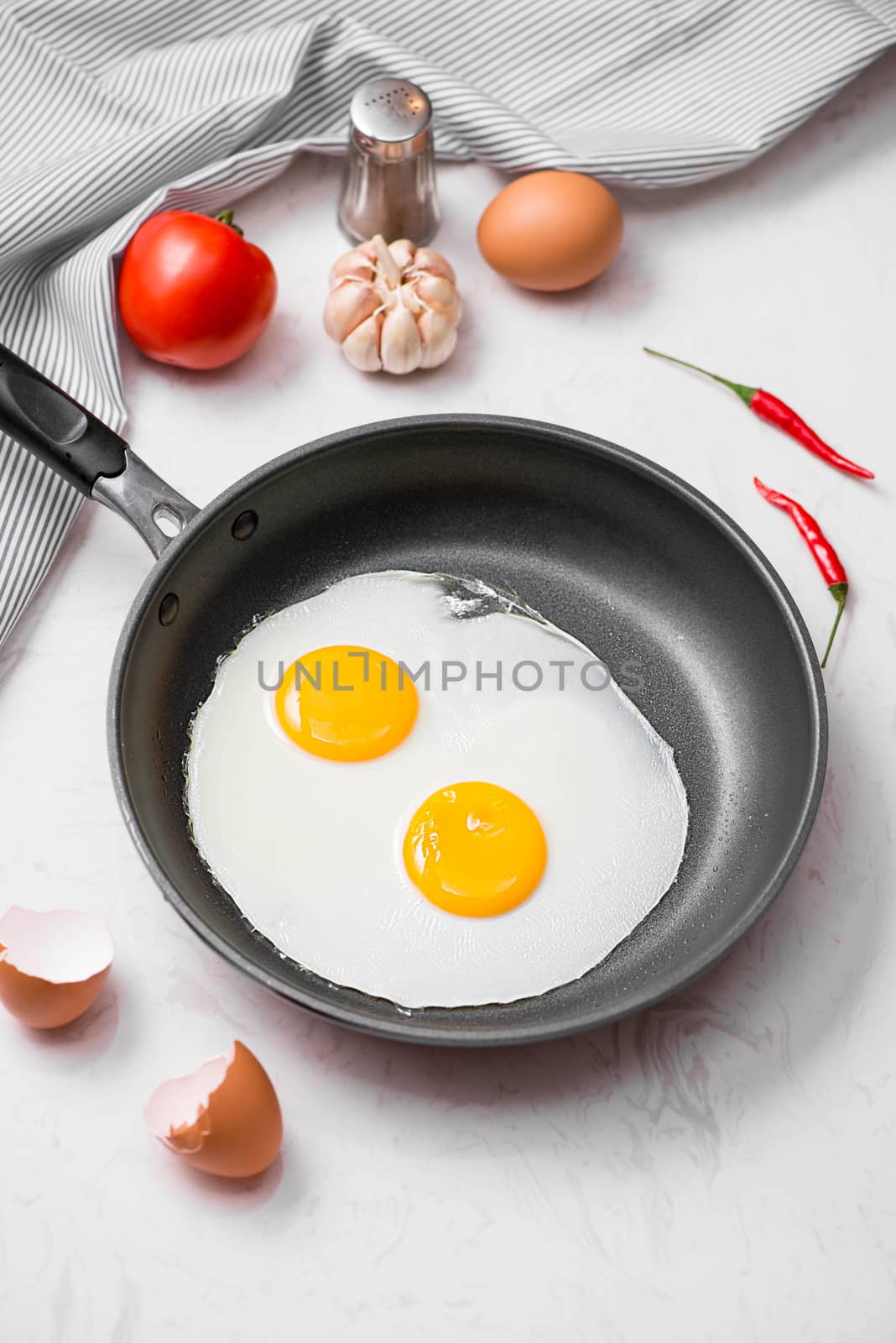 Fried eggs in a frying pan with cherry tomatoes and bread for breakfast