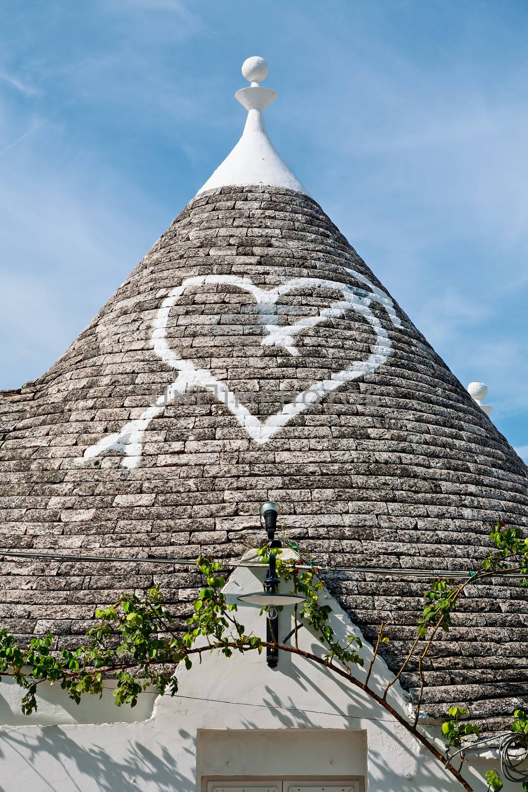 Symbol in the Trullo conical rooftop in Alberobello under a blue sky, Apulia, Italy