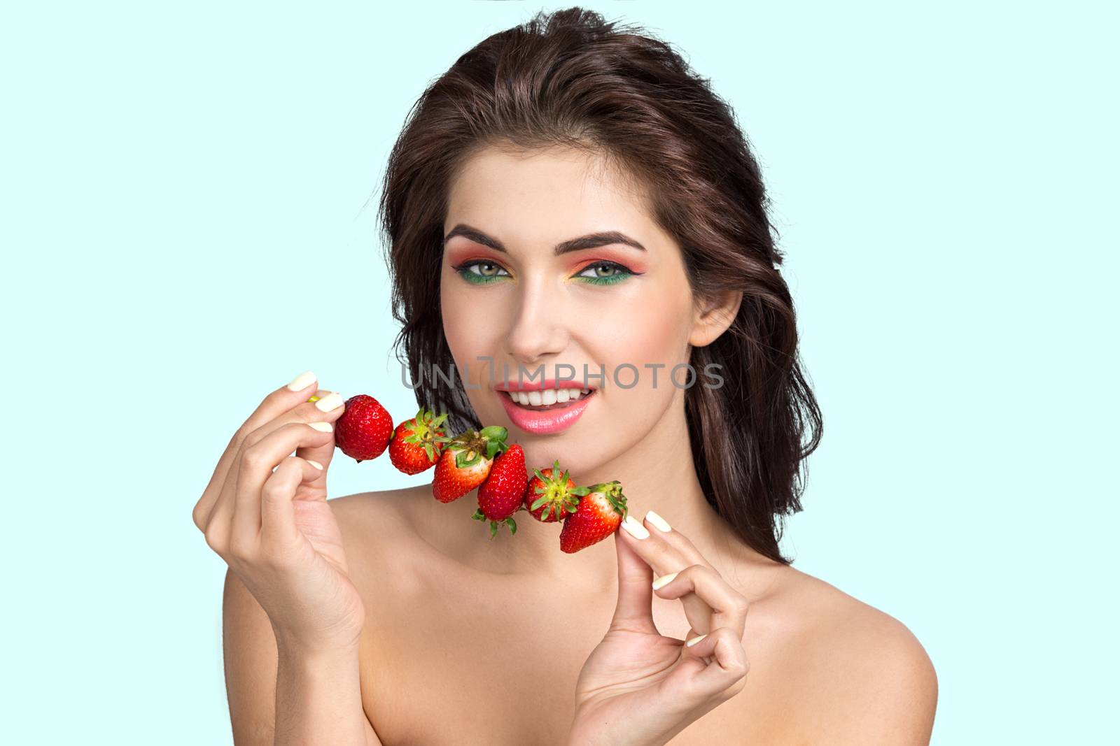 Beautiful young woman with strawberry sticked on skewer