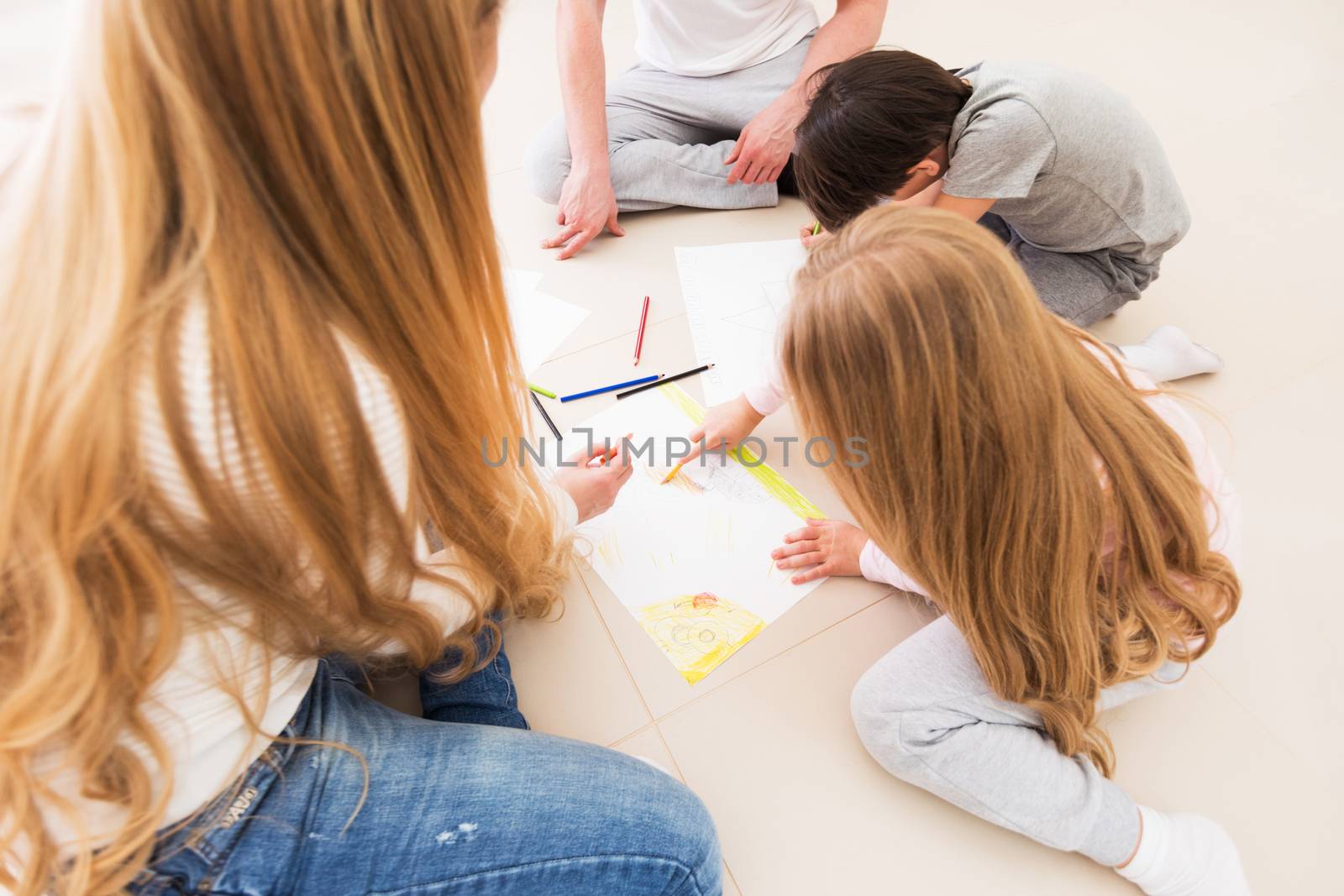 Parents and children drawing with pencils on the floor