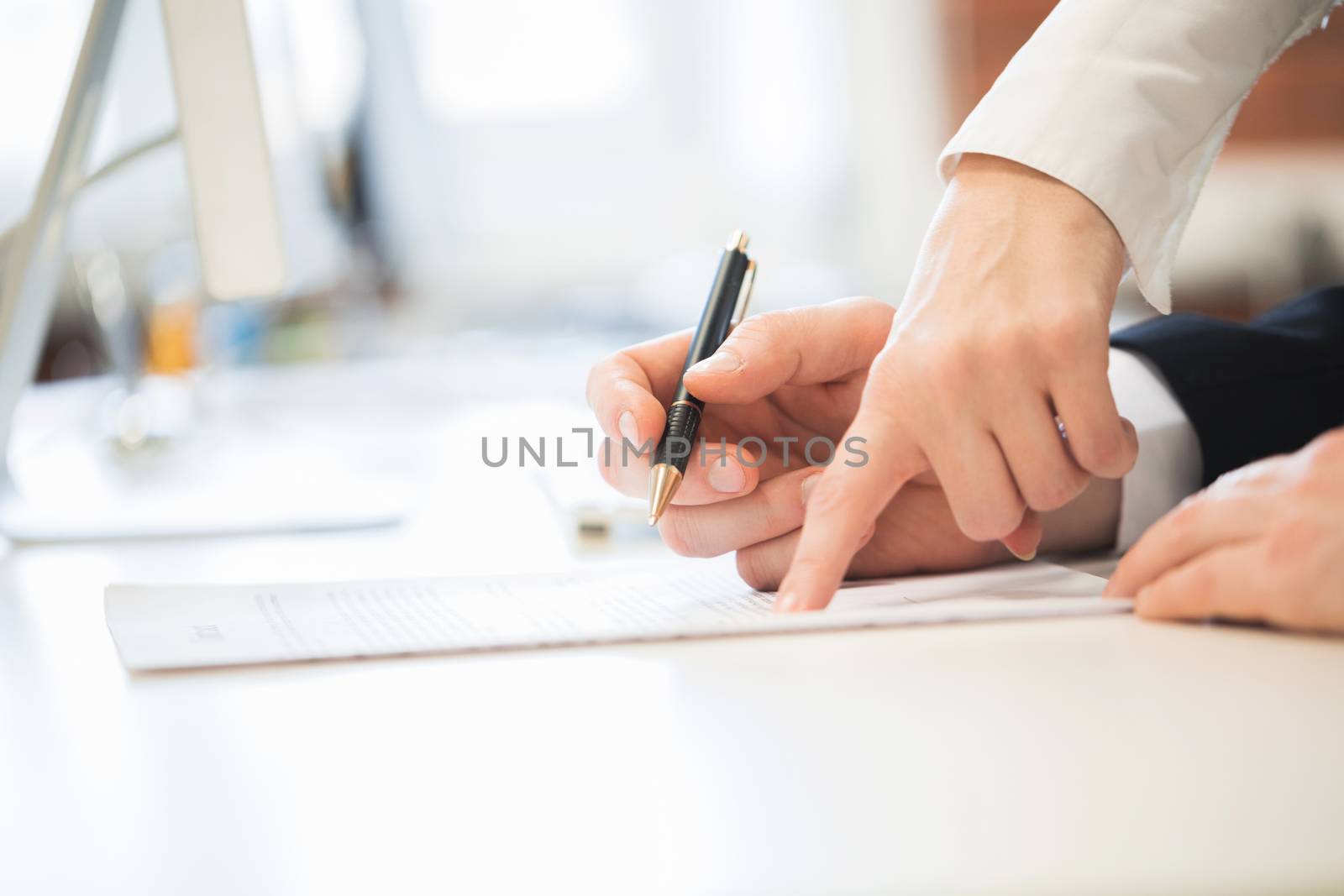 Detail of a man signing a contract and woman showing where to sign