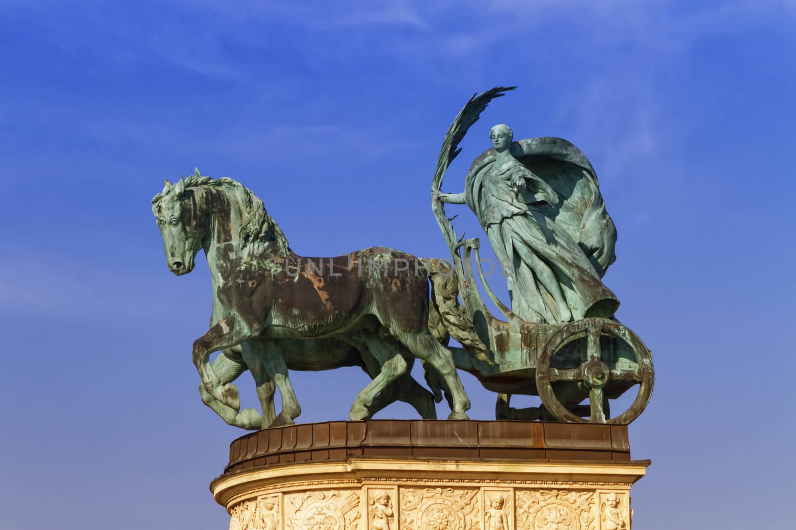 Statue representing Peace, a woman holding a palm frond on a chariot, on a colonnade in Heroes Square or Hosok Tere by day, Budapest, Hungary.