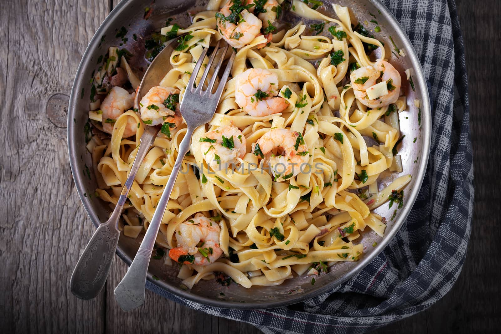 Tagliatelle with shrimps on the pan with fork and spoon