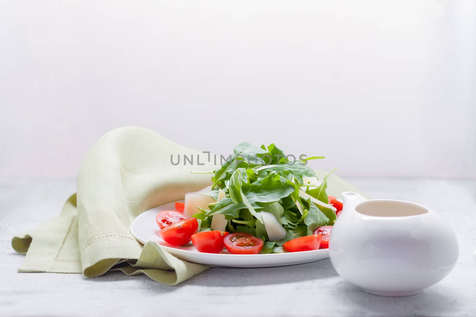 Salad with arugula, tomatoes and greenery on a white plate