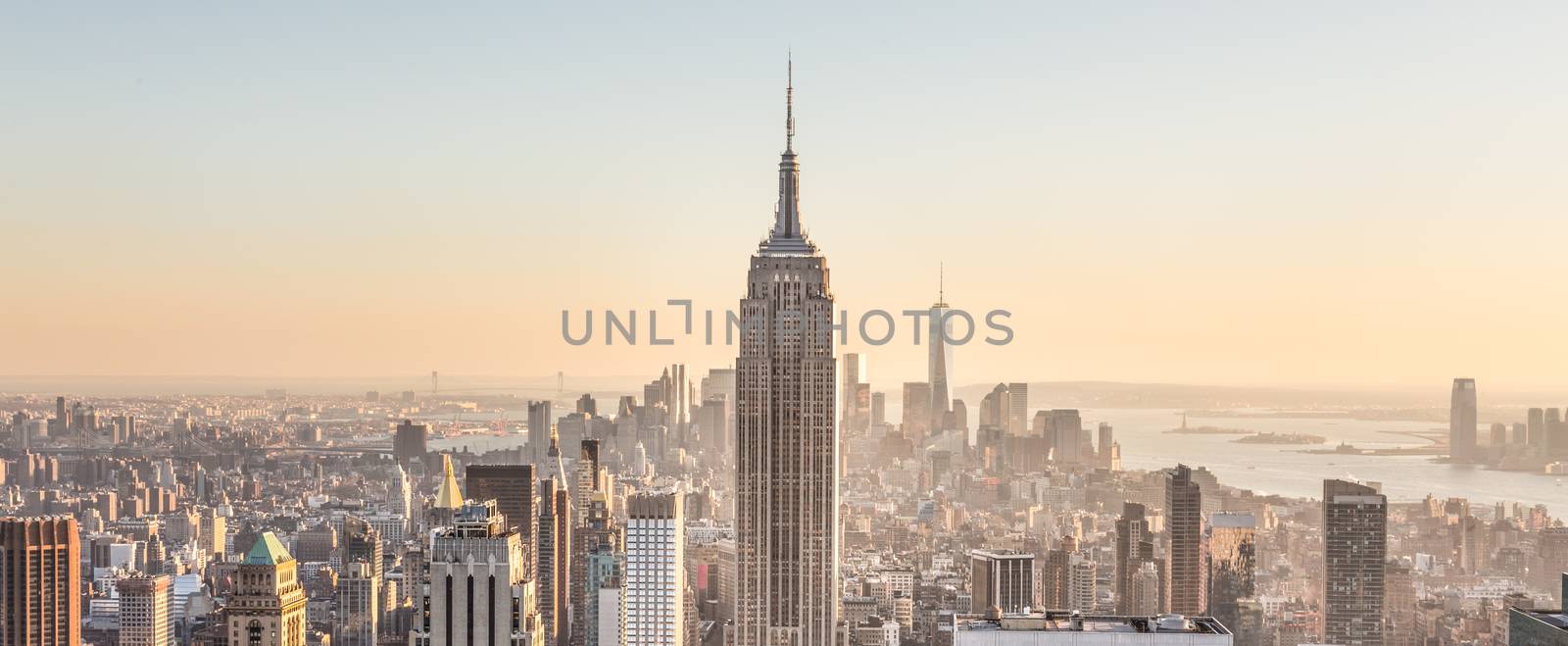 New York City. Manhattan downtown skyline with sun illuminated Empire State Building and skyscrapers at sunset.