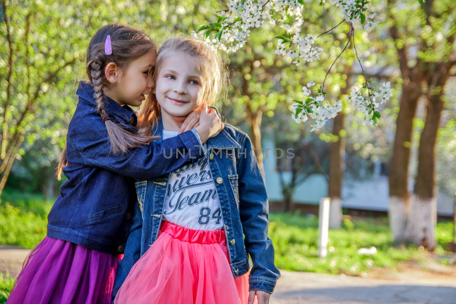 Two girls telling secret among spring garden