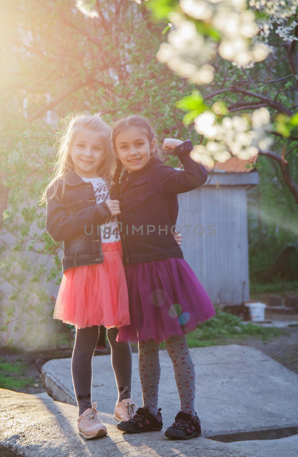 Two girls enjoying garden at sunset by Angel_a