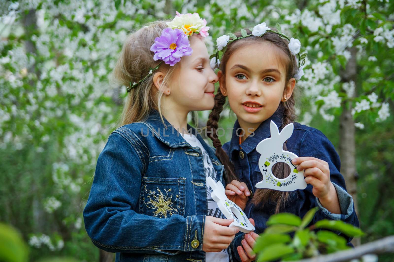 Two girls with toy bunnies telling secrets on ear