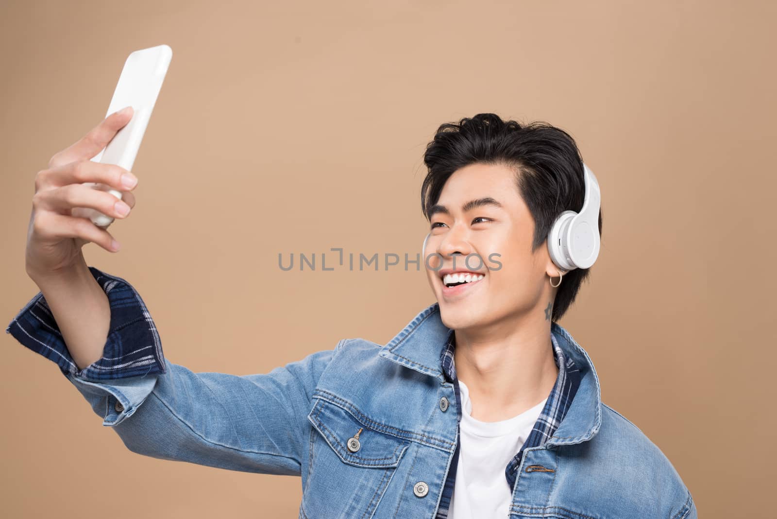 Portrait of a young asian handsome man with headphones smiling and listening to music