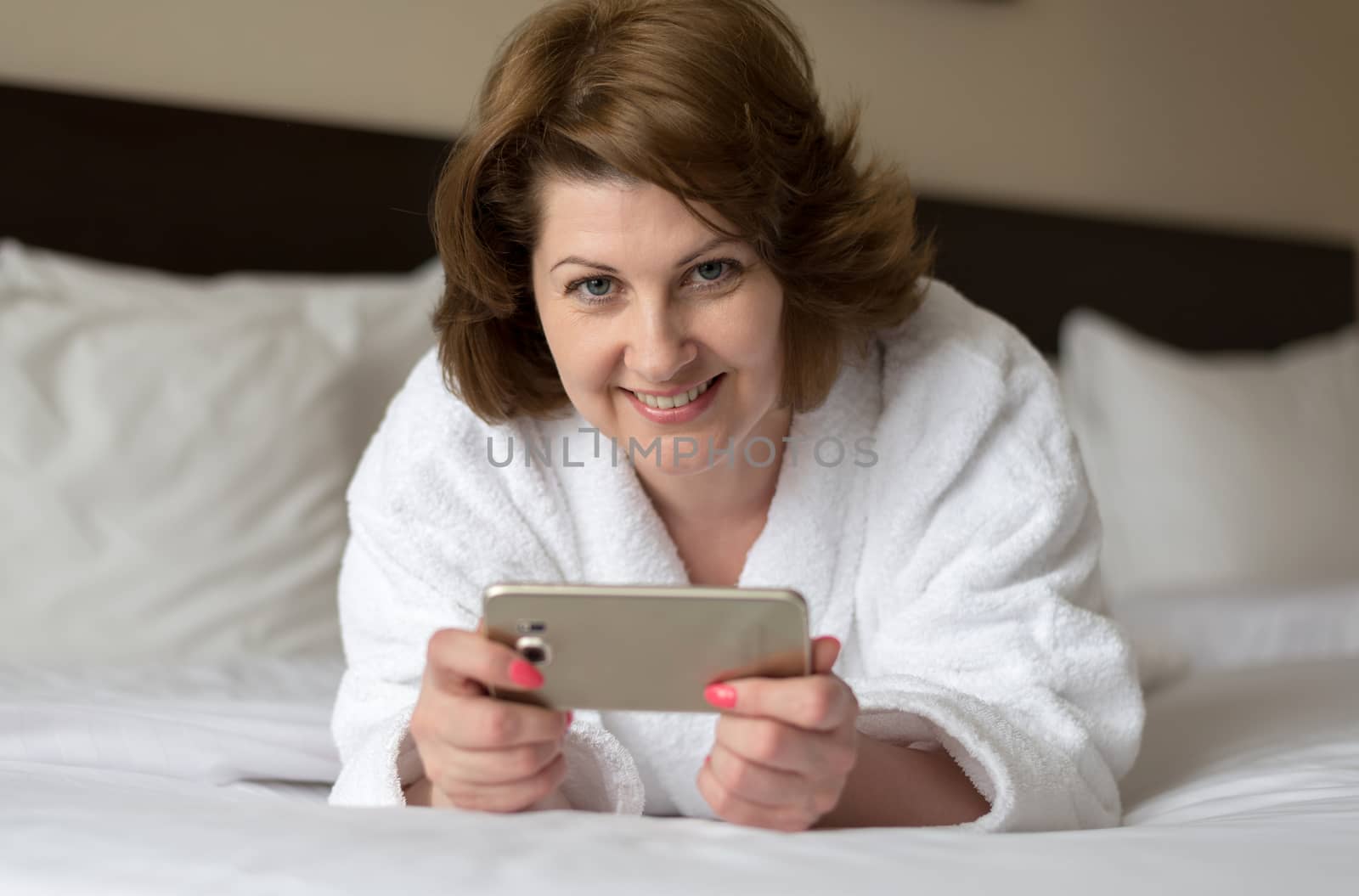 A woman in a bathrobe wears a telephone in the hotel room