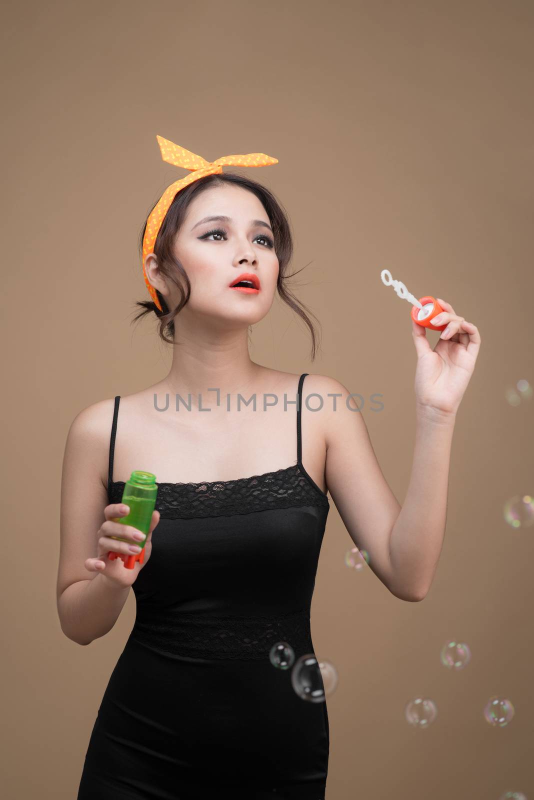 Playful pinup woman blowing party bubbles over yellow background by makidotvn