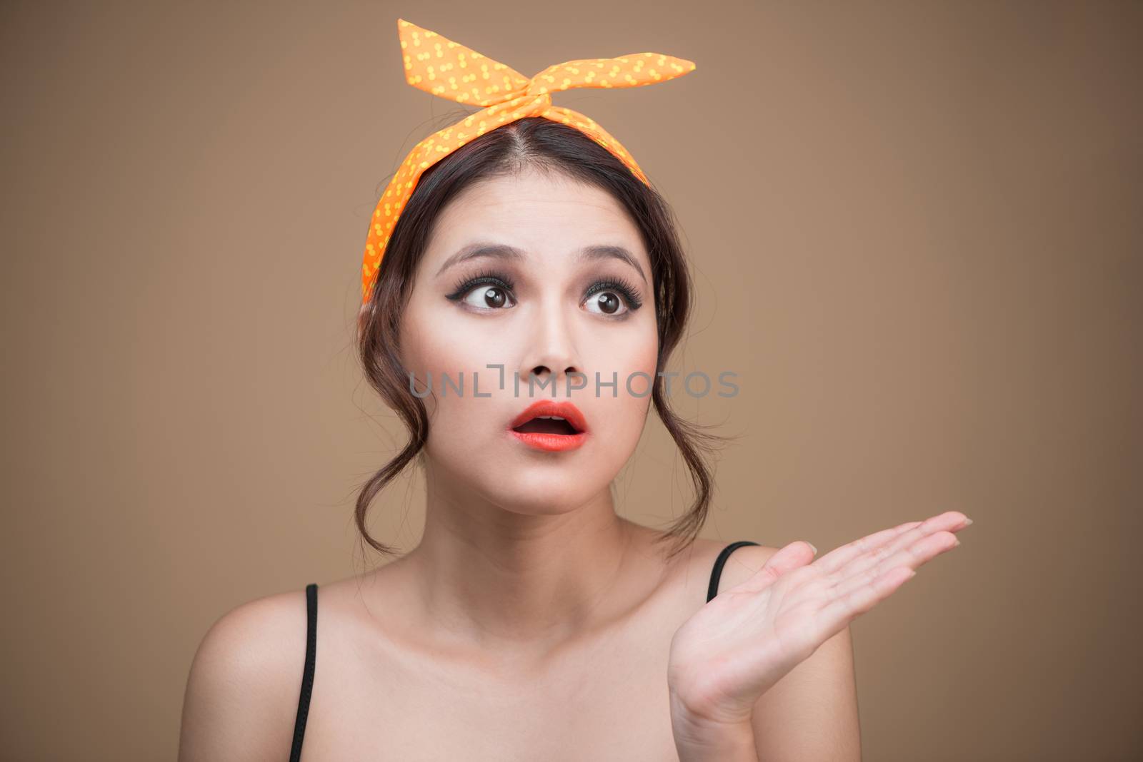 Surprised asian girl with pretty smile in pinup style on yellow background