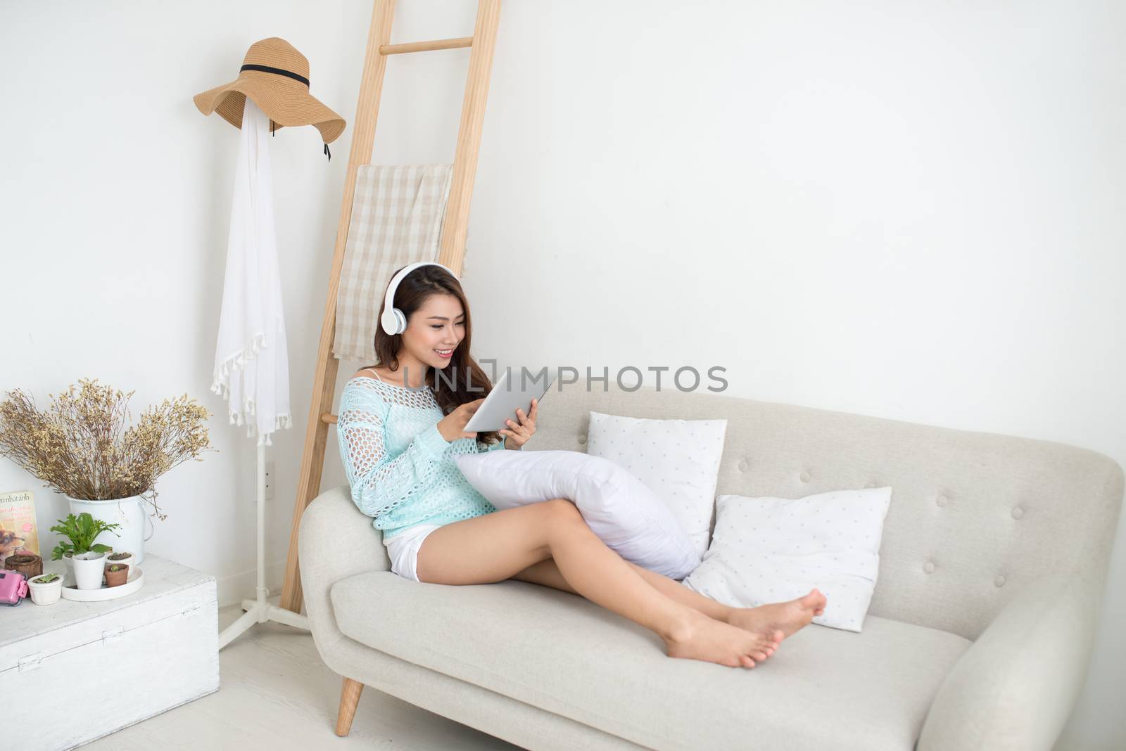 Asian woman enjoying sitting on couch and listening to music.