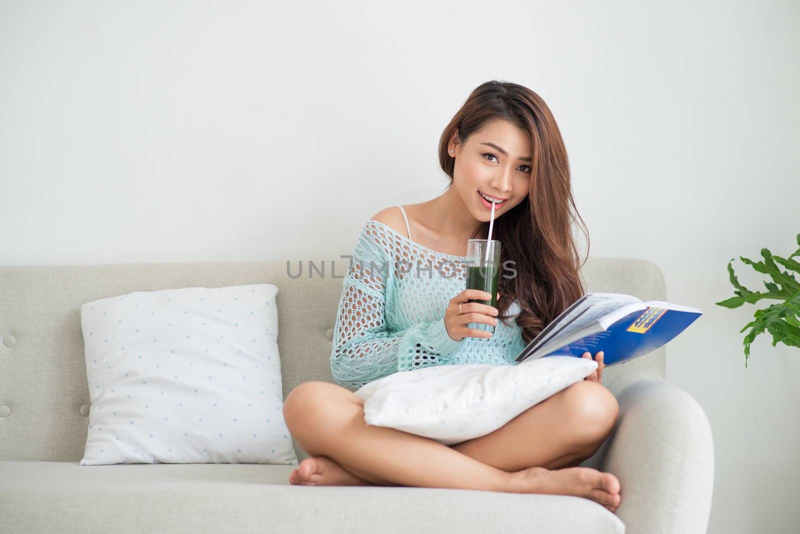 Pretty young asian woman drinking green fresh vegetable juice or by makidotvn