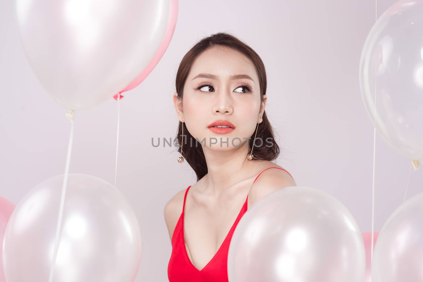 Asian beautiful woman in red dress with pastel balloons and looking up