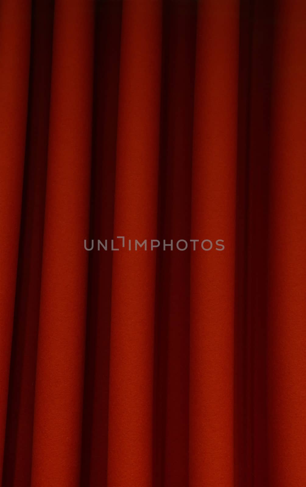 Heavy dark red pleated textile felt curtain background with portiere drape folds, side view close up