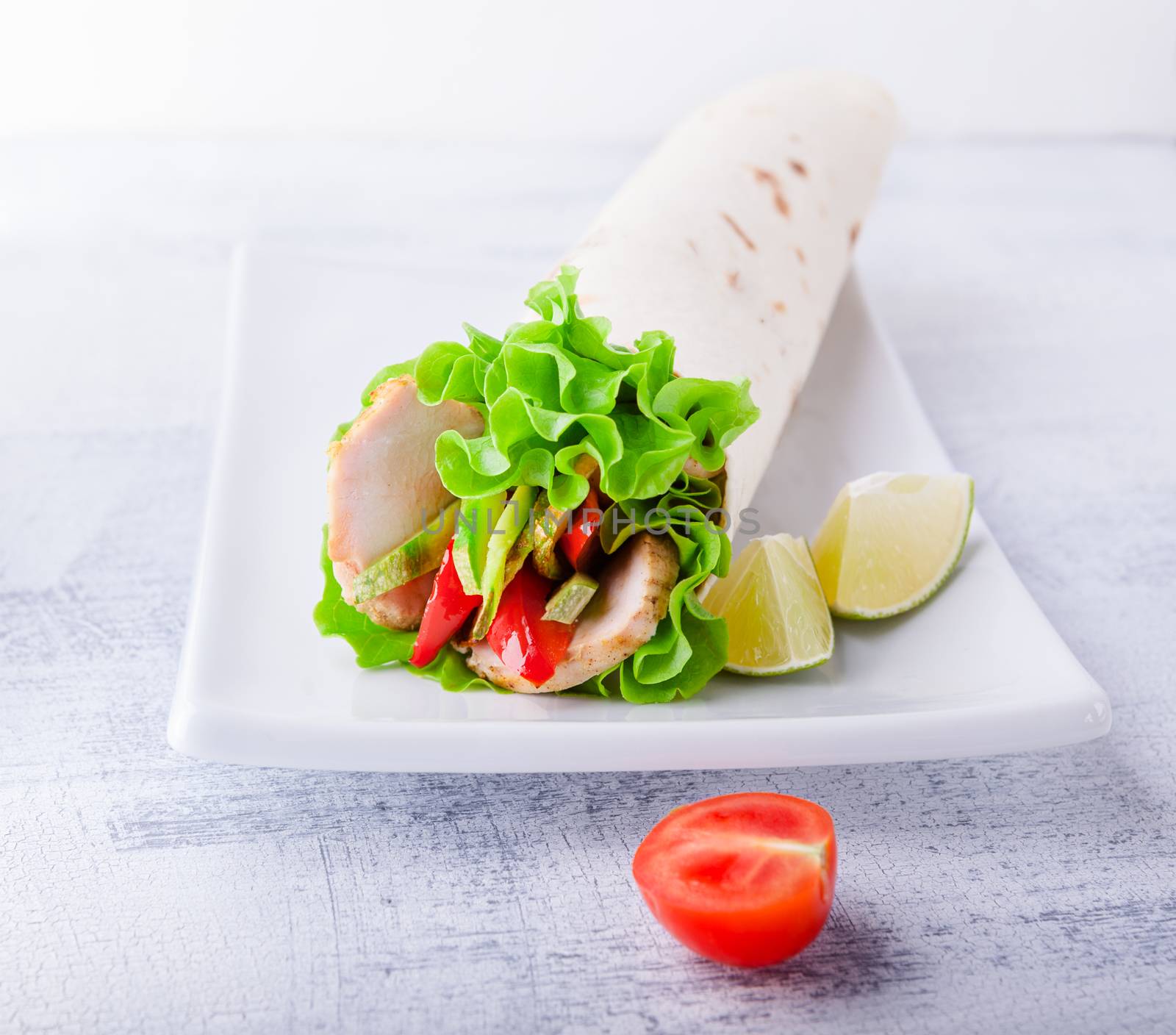 Sandwich wrap with garden salad, chicken, lettuce and tomato in a whole wheat tortilla 