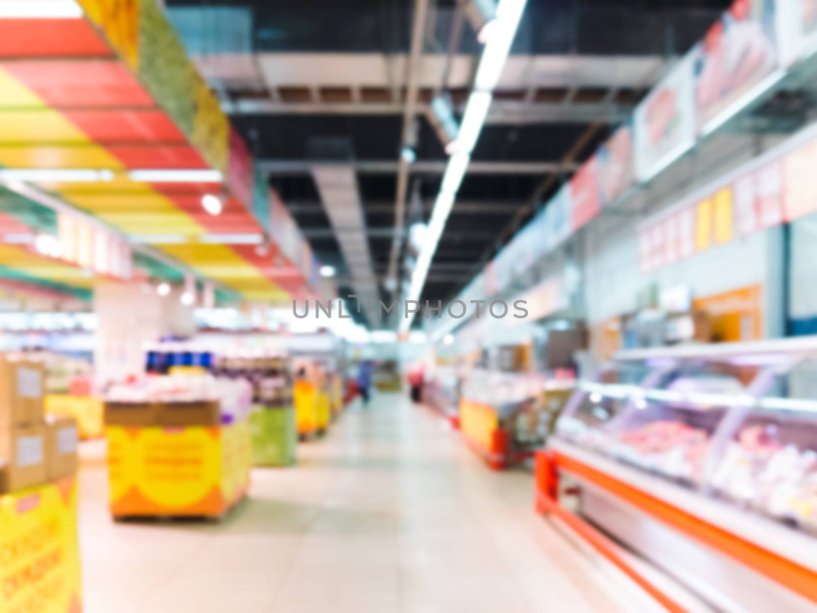 Abstract blurred supermarket aisle with colorful shelves with refrigerator as background