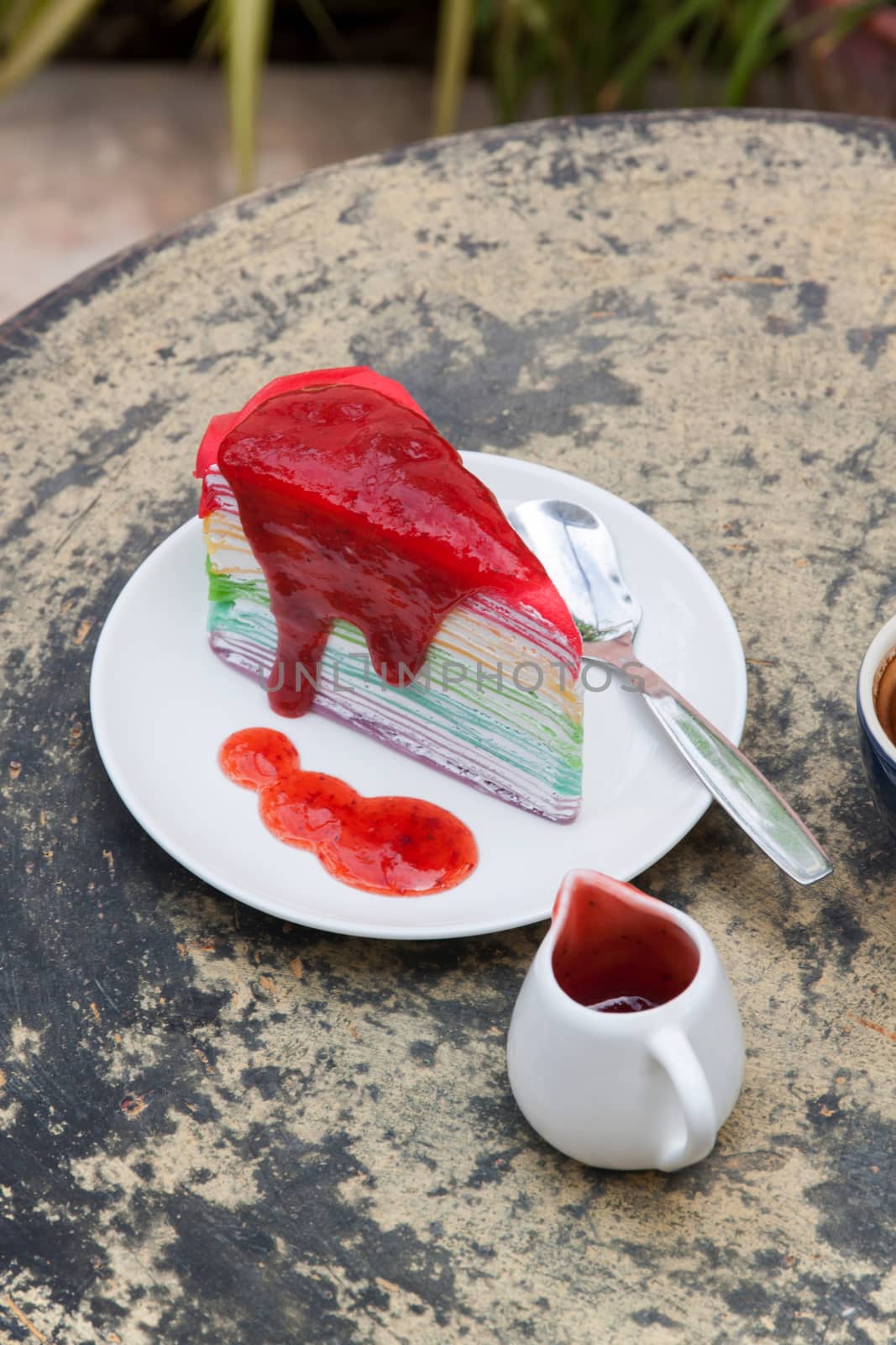 crape cake rainbow and hot espresso coffee in garden side home. crape cake with strawberry sauce