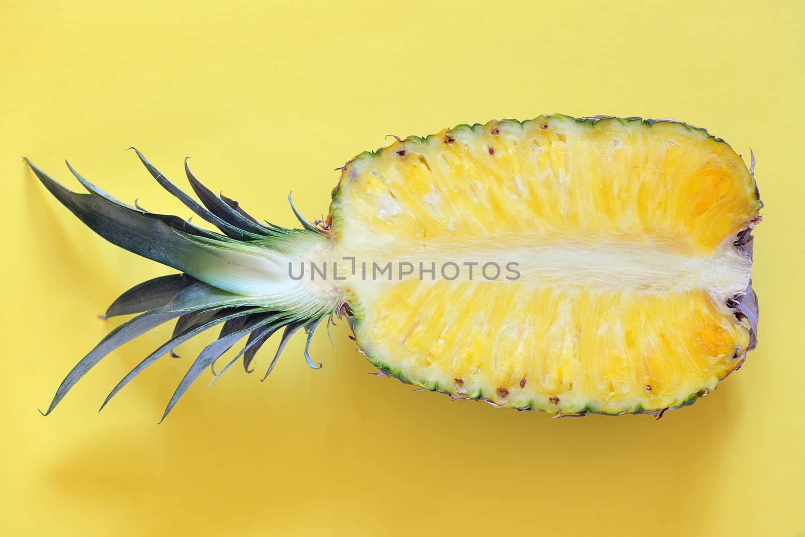 Raw cut pineapple on yellow surface table 