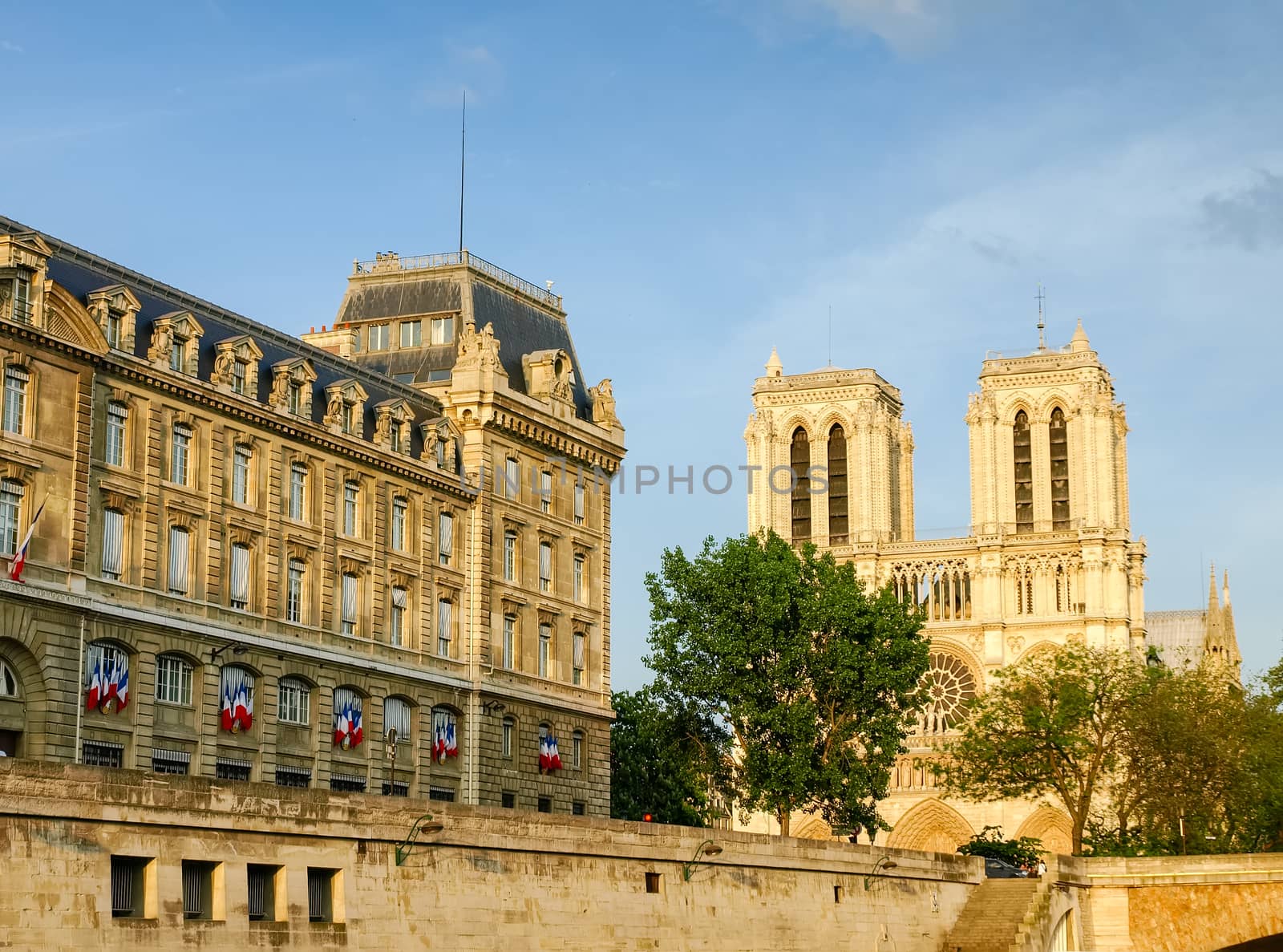View of the west facade of the Cathedrale Notre-Dame de Paris and part of the building of Police prefecture from the Seine in the spring evening
