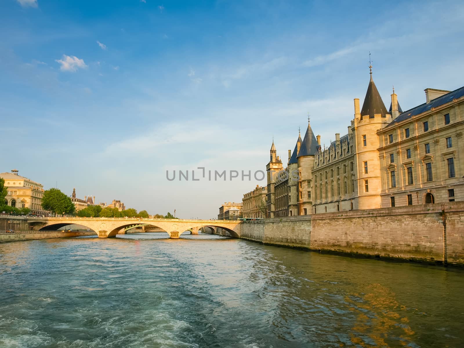View of the several bridges over river Seine and the Conciergerie Palace from the river in the spring evening in Paris, France
