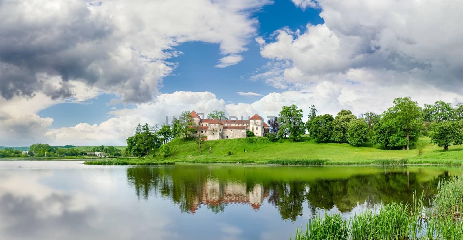 Svirzh Castle built in the 15th century on the lake bank after spring thunderstorm in Lviv region, Ukraine 
